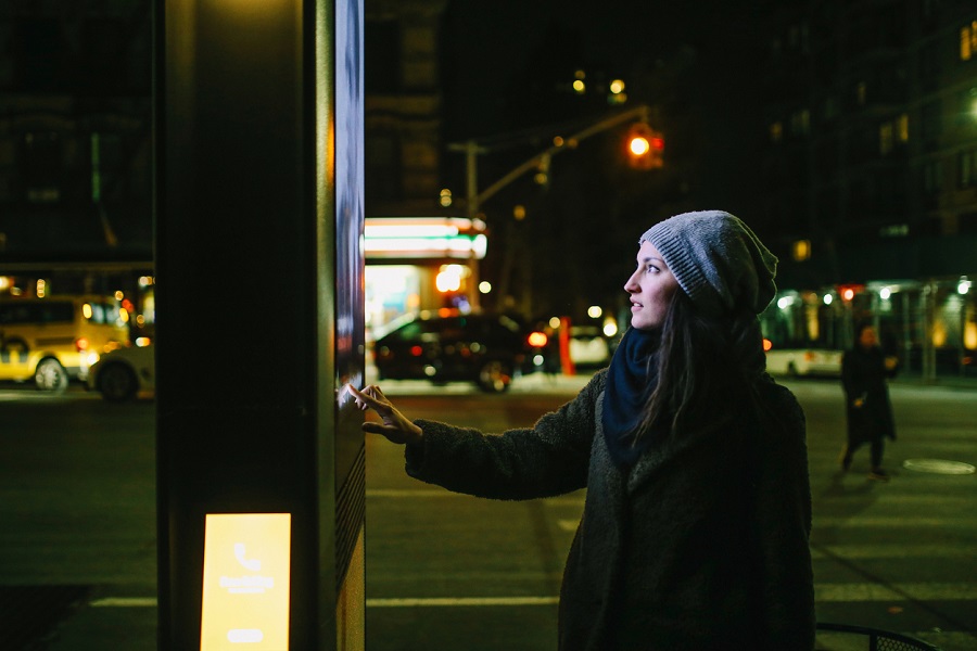 Young woman using interactive touch screen city display to check for information, New York City, USA.